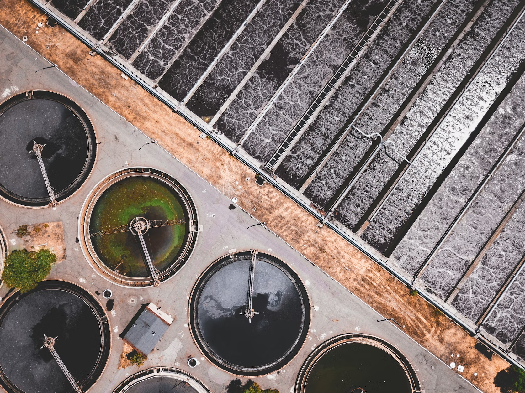 Aerial view of a wastewater treatment plant showing settlement tanks and filtration channels
